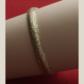 Nyt armbnd med afdmpet guldglitter og charm. 5 indstillingshuller. Nypris 299kr.