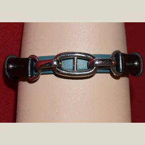 Armbnd i turkis lder og slvkde holdt fast med sorte lderbnd. Returvare uden brugsspor.