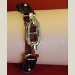 Armbnd i mrkbrunt lder og guldkde holdt fast med sorte lderbnd. Returvare uden brugsspor.